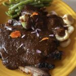 Photo shows a plate of food covered with a smooth dark sauce