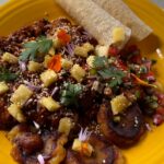 Photo shows a plate of food covered with a dark brown sauce with pineapple bits and colorful salsa