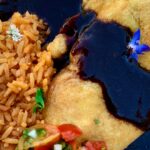 Photo shows a plate of chile relleno with molé Colorado