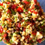 Photo shows a bowl of vibrant red, yellow and green corn salsa