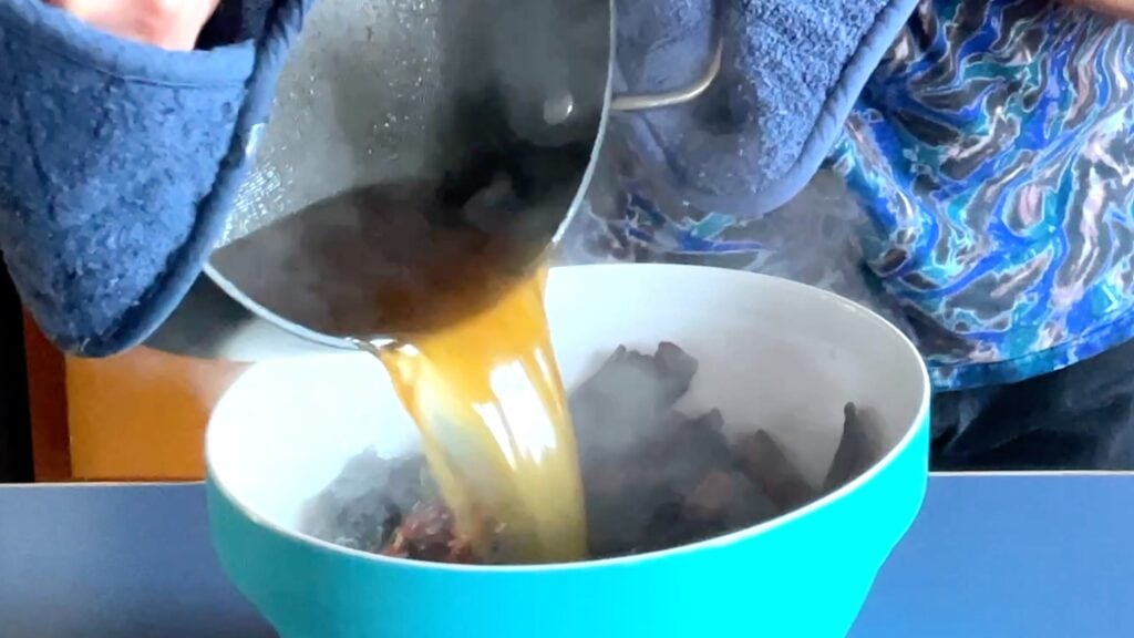 Photo shows boiling broth being poured over the chiles