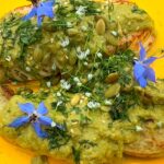 Photo shows a plate of food covered with a green sauce.