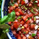 Photo shows a bowl of salsa with cilantro on the side.