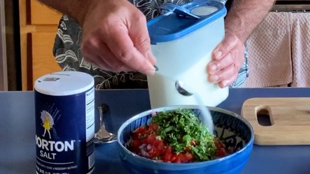 Photo shows sugar being added to the bowl of chopped vegetables
