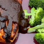 Photo shows fish plated with sauce and broccoli