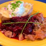 Photo shows duck plated with cherry sauce, baked potato and garnish