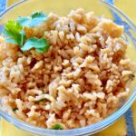 Photo shows a bowl of Mexican Rice on a yellow tile countertop