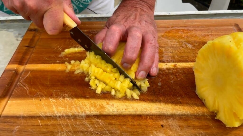 Photo shows making cuts iin the opposite direction to make cubes of pineapple