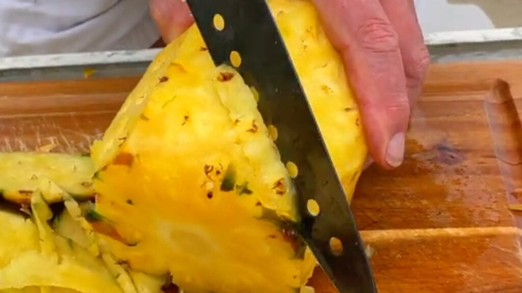 Photo shows making a v cut down the pineapple