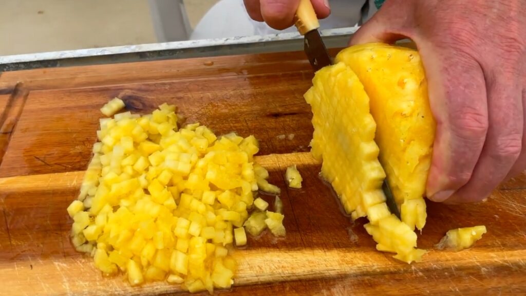 Photo shows cutting cubes off the end of the pineapple