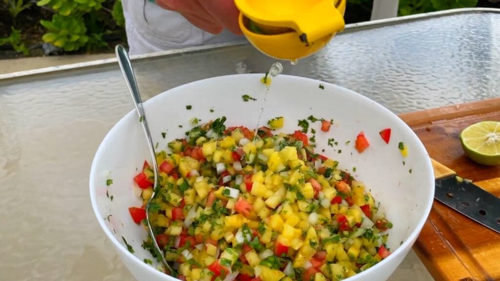Photo shows lime being squeezed into the salsa.