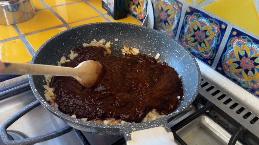 Photo shows the Chile Paste being added to the onions