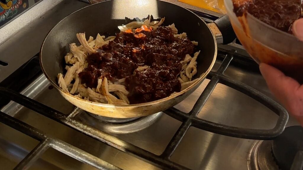 Photo shows molé and shredded chicken in a pan