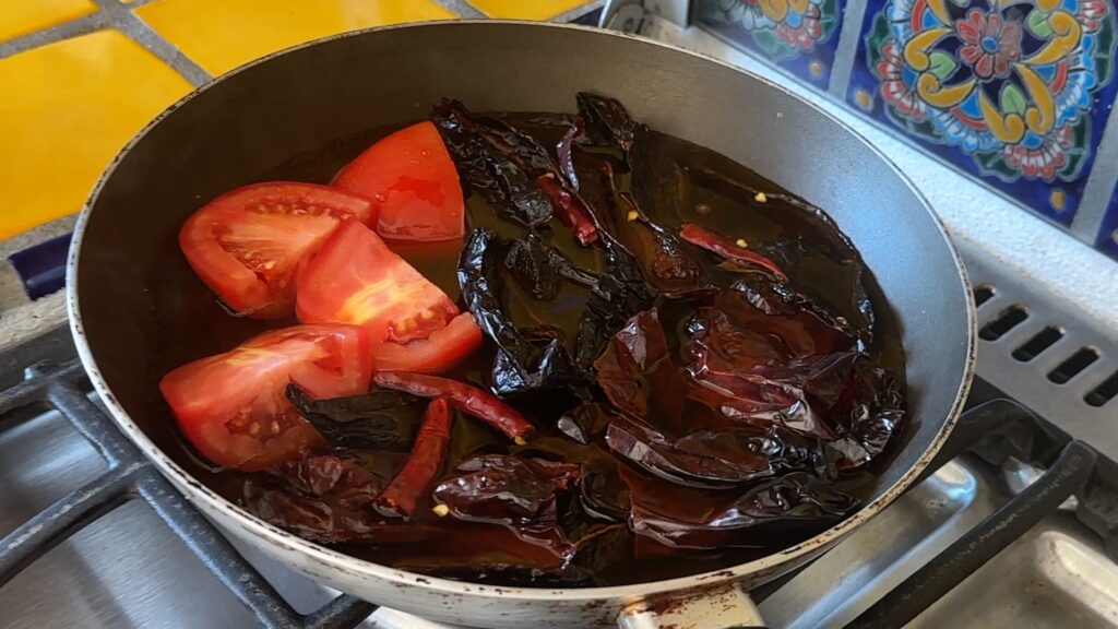 Photo shows Chiles and Tomatoes in the pan with water.