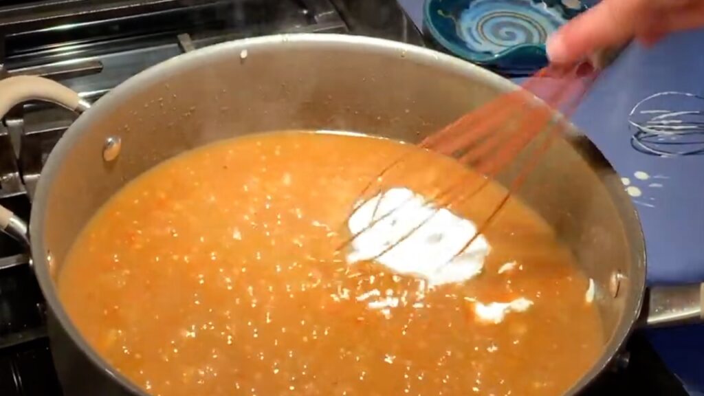 Photo shows the sour cream being wisked in to the bubbling sauce