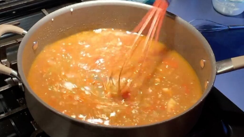 Photo shows the flour slurry being wisked in to the sauce