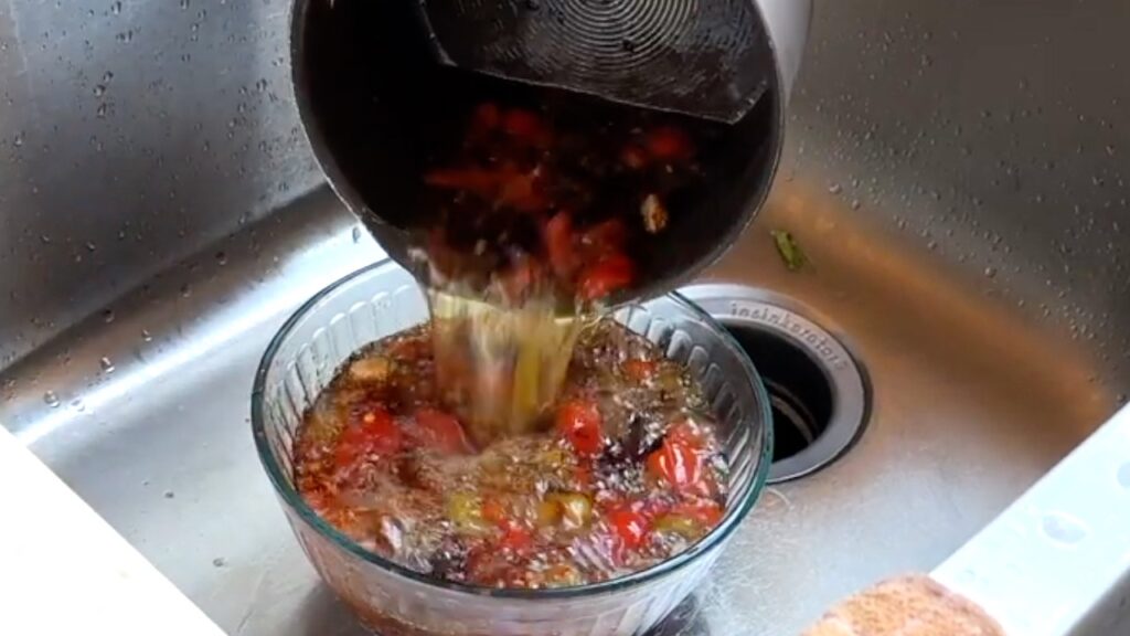 Photo shows the hot oil being poured into the bowl of chile flakes