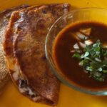 Photo shows quesabirria tacos with consommé