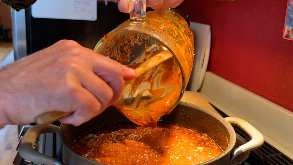 Photo shows the chile sauce being added back to the pot.