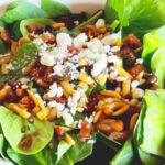Photo shows a spinach salad with hot dressing and feta cheese