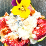 Photo shows the finished baked fig served with an edible flower garnish